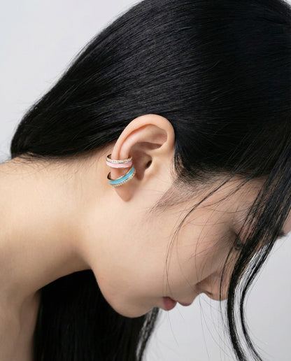 Minimal styling with layered enamel ear cuffs in turquoise and pink, shown from side profile