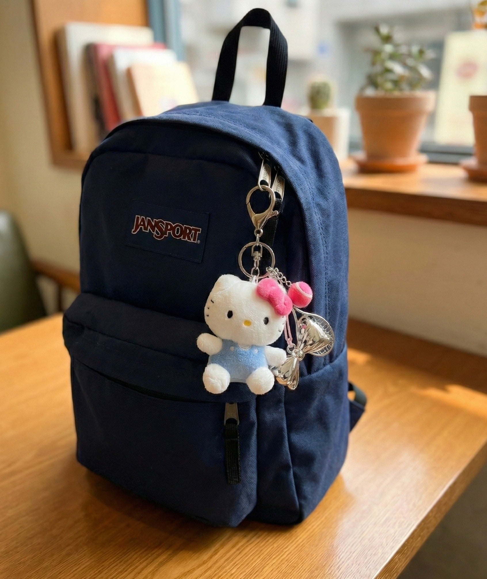 Hello Kitty plush keychain on navy Jansport backpack — tenniscore aesthetic school bag charm