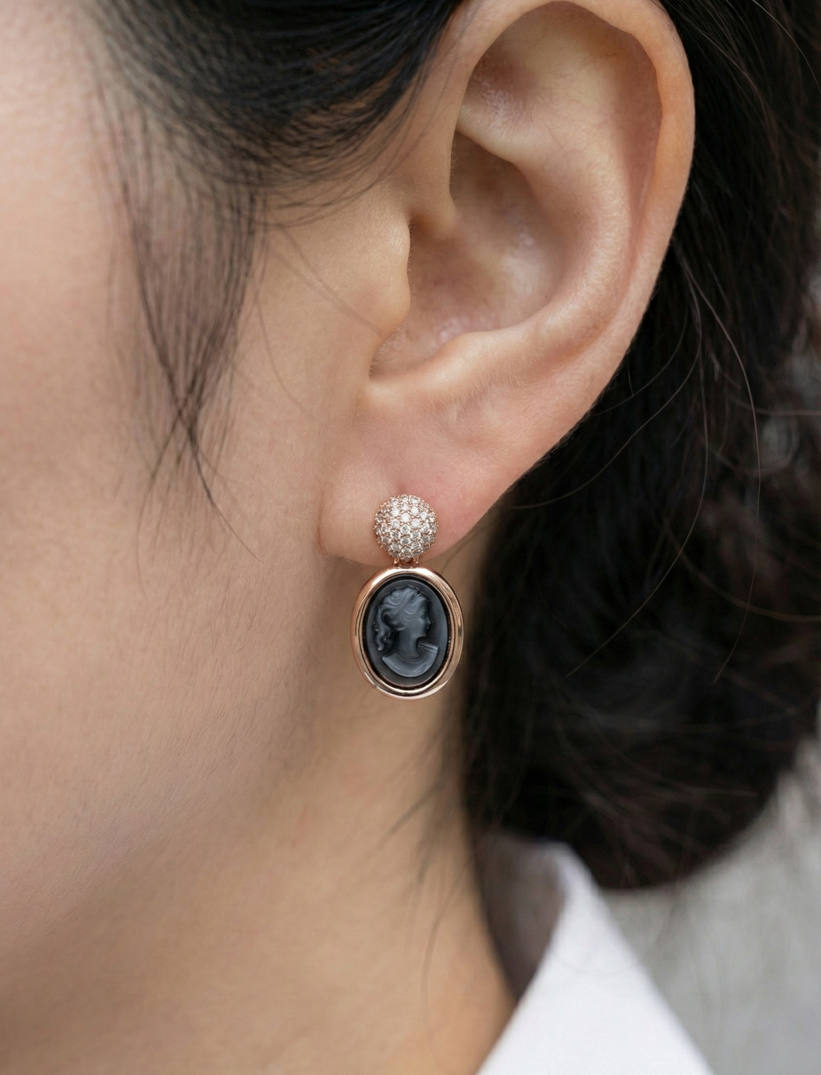 Close-up of woman wearing black vintage cameo earring with crystal stud