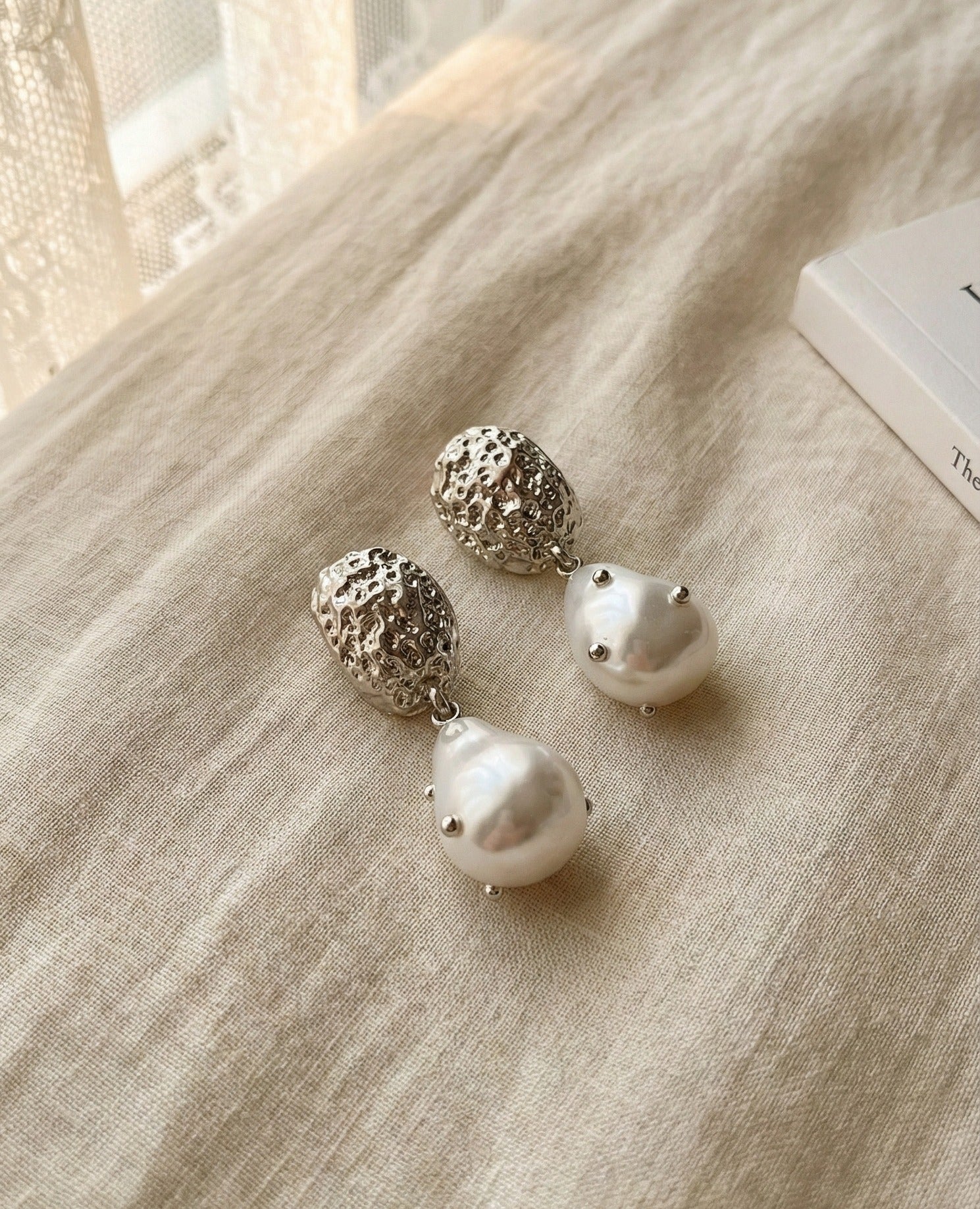 Close-up detail of silver hammered baroque pearl earrings showing texture