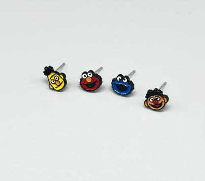 Four Sesame Street character earrings displayed individually showing Bert Elmo Cookie Monster and Ernie with 925 sterling silver posts