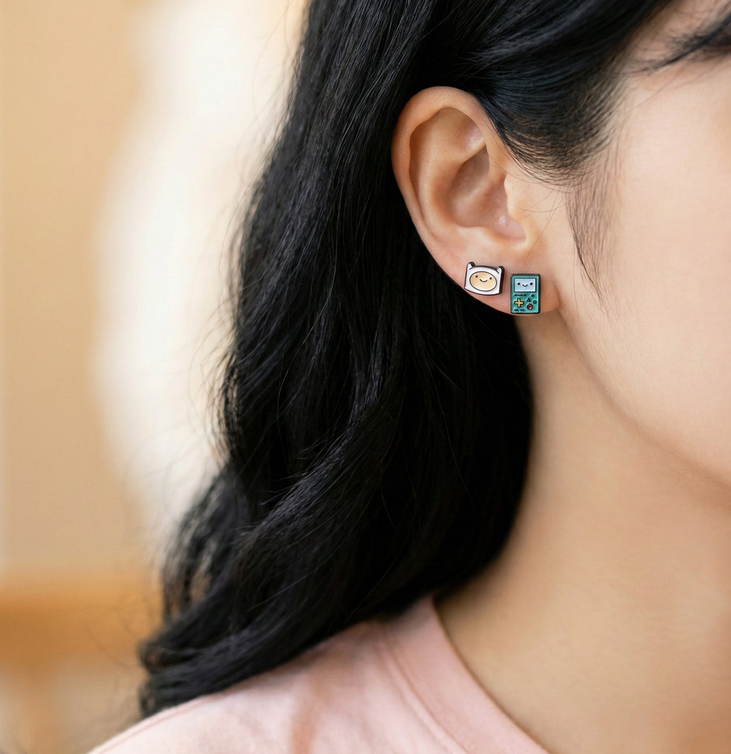 Side view of woman wearing Adventure Time Finn and BMO stud earrings, minimalist styling