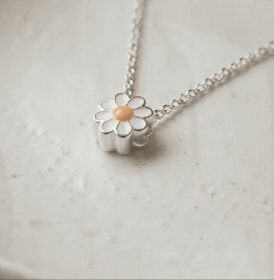 Animated macro shot of 925 sterling silver daisy pendant with white and yellow enamel, gentle light movement
