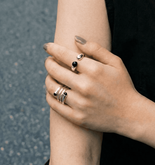 Model crossing arms wearing black onyx sterling silver open rings on both hands — black outfit close-up