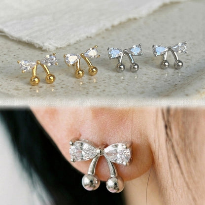 Collage showing gold and silver CZ bow cherry studs flat lay on top, and silver version worn on ear close-up on bottom, demonstrating both colorways and actual wear size