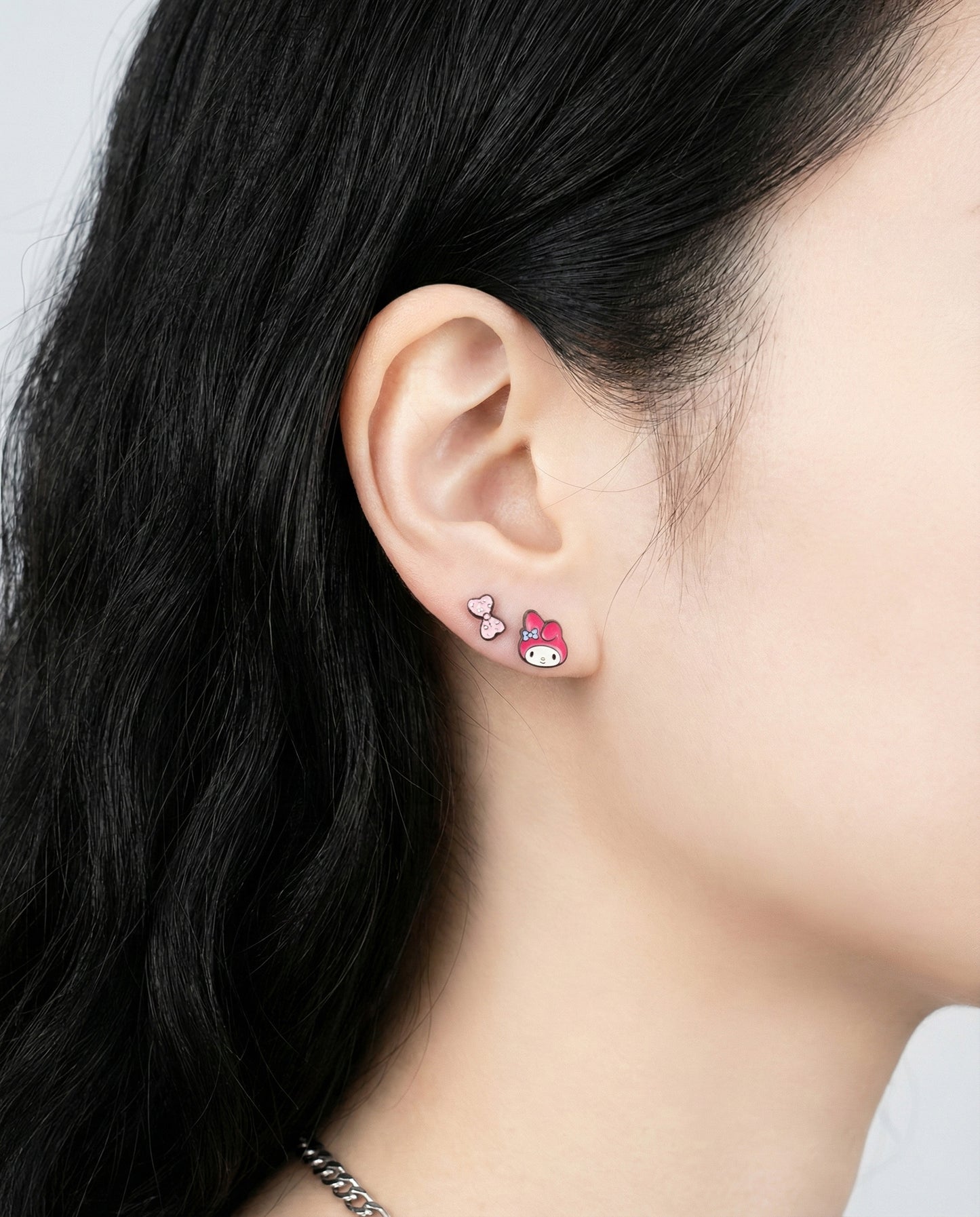 My Melody character earrings with pink ribbon and cupcake studs worn as layered piercings
