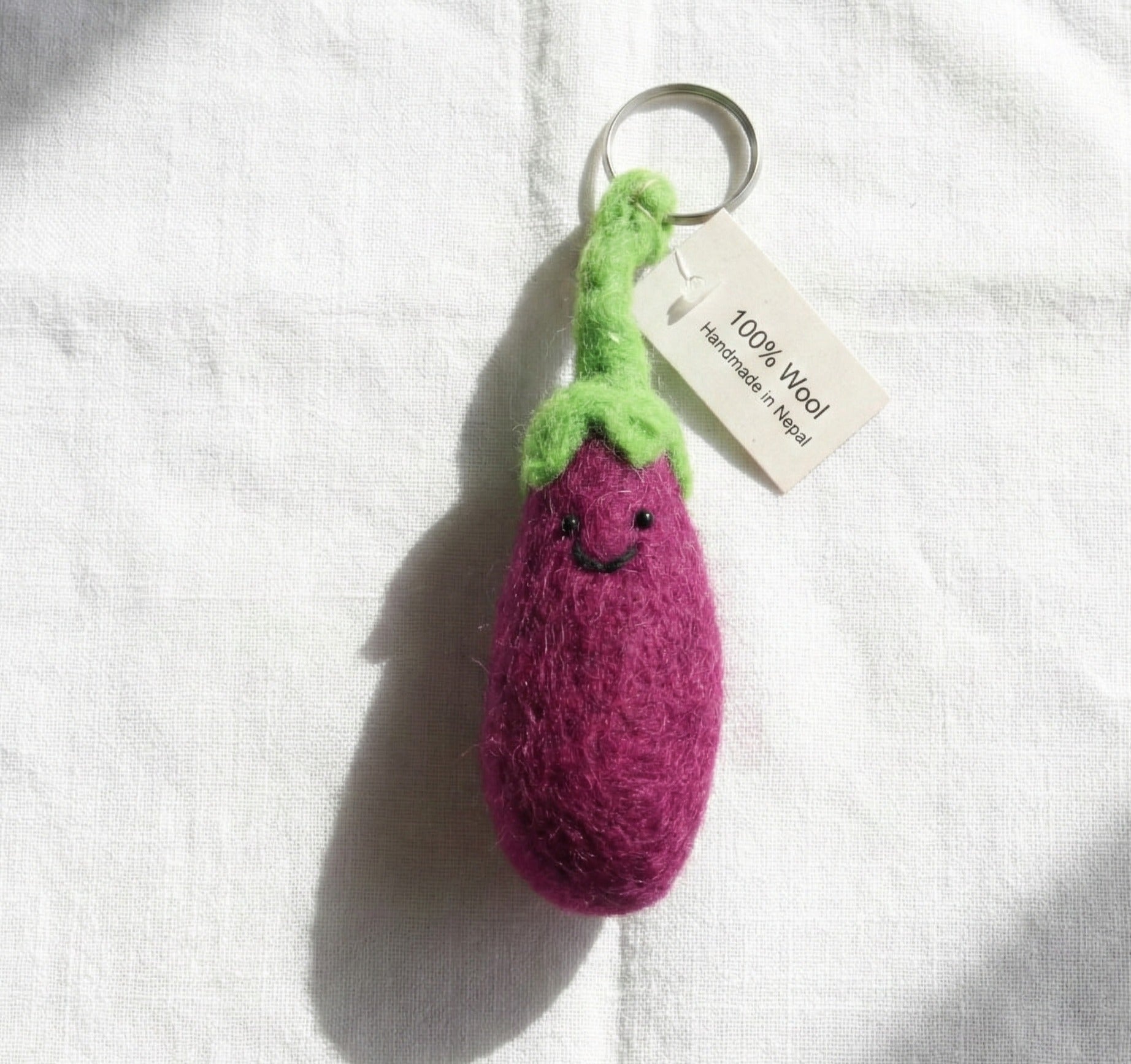 Purple eggplant felt keychain with green stem on white background