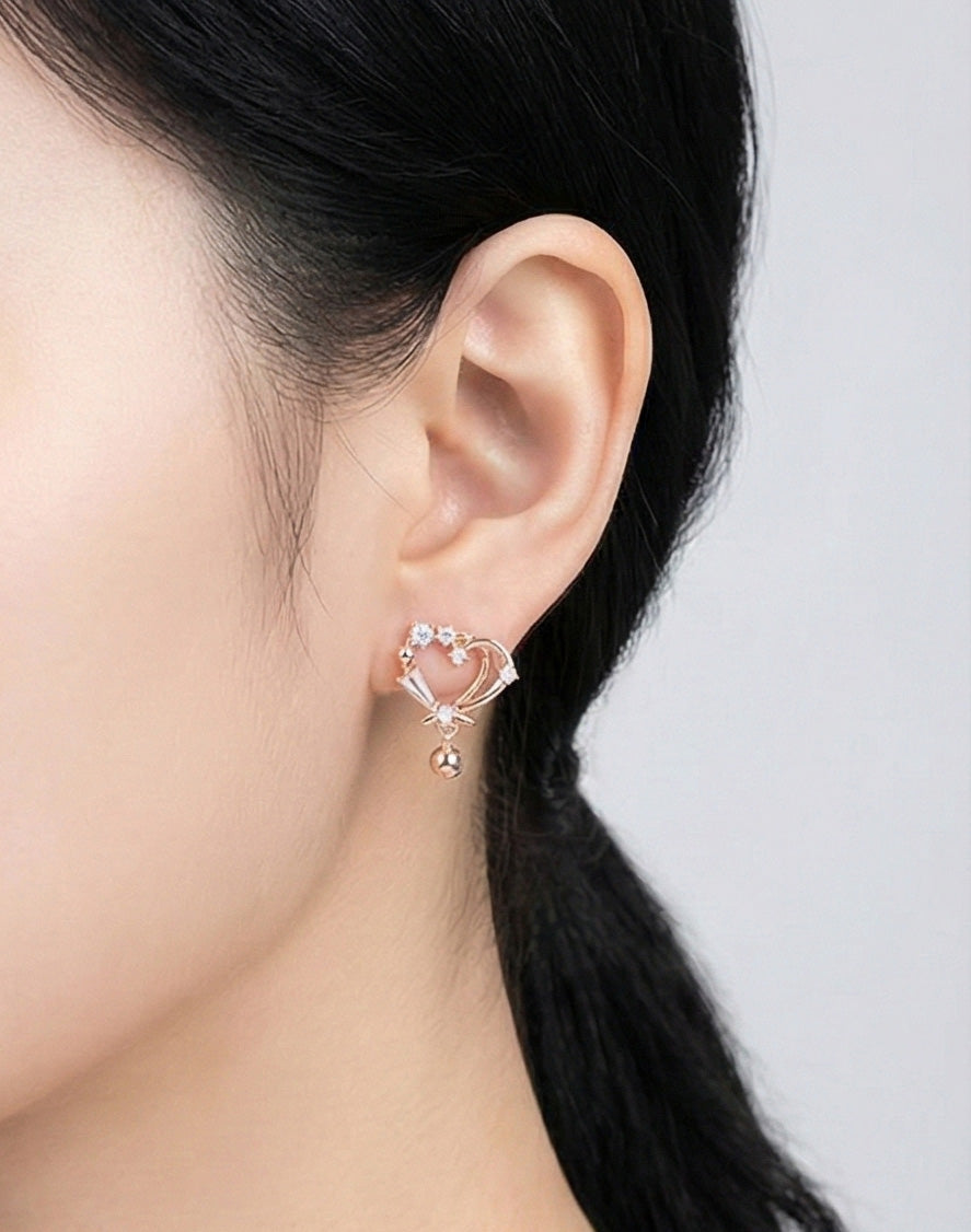 Woman wearing rose gold heart drop earrings with sparkling cubic zirconia and dangling bead, side angle showing comfortable everyday fit, Korean jewelry with 925 silver posts