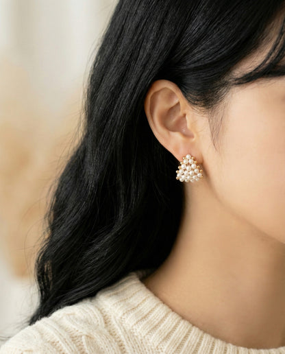 Woman wearing gold pearl heart C-hoop earrings with cream knit sweater - side profile