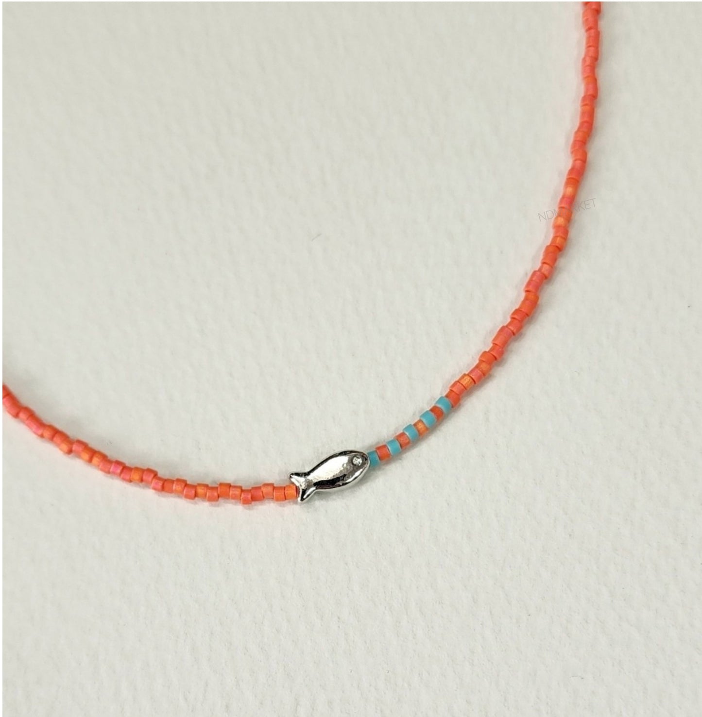 Detail shot of tropical orange seed bead choker with silver fish pendant and turquoise accent beads