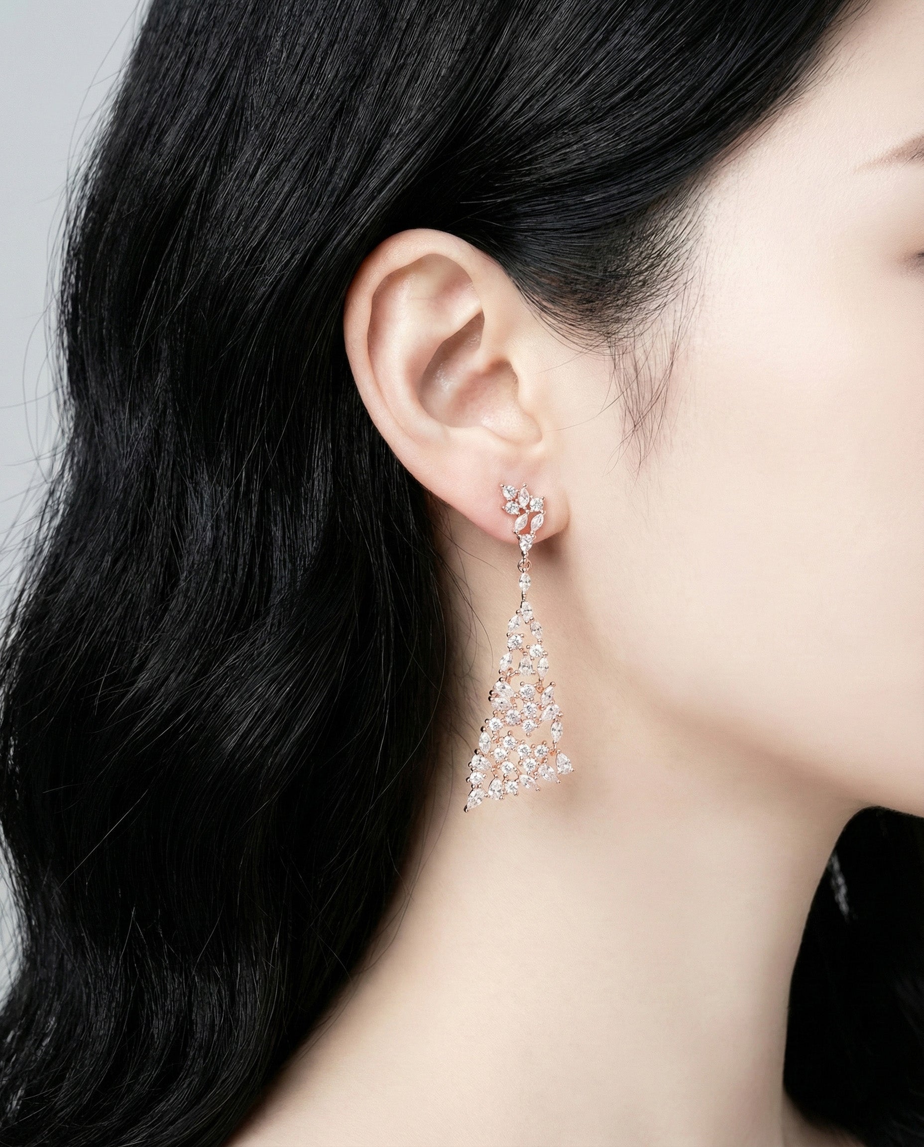 Close-up of rose gold chandelier earring detail on ear