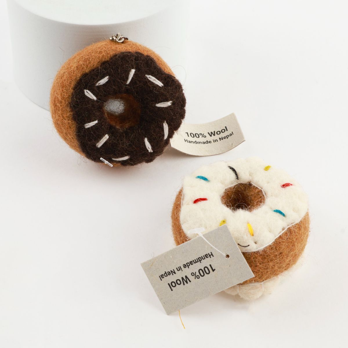 Two wool felt donut keychains - chocolate and vanilla with sprinkle details and 100% wool handmade in Nepal tags