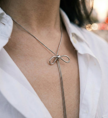 Woman wearing silver bow lariat necklace with white shirt - elegant office styling