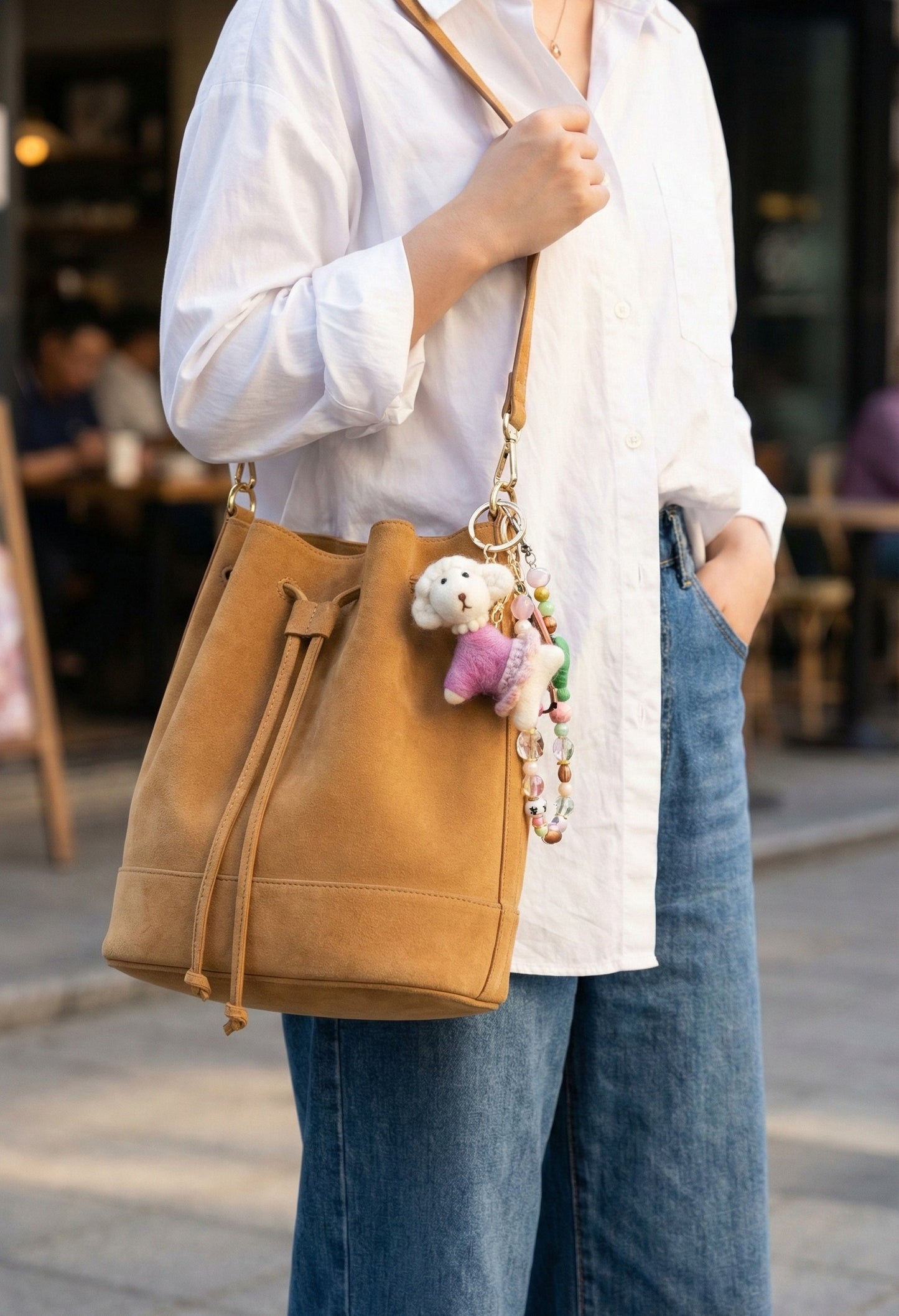 Poodle bag charm styled on camel bucket bag with beaded strap in street fashion shot