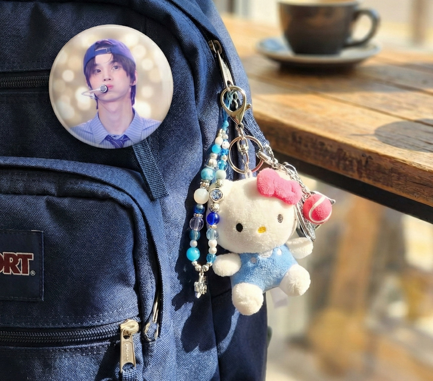 Hello Kitty tennis keychain layered with beaded keychain and K-pop photo card badge on backpack