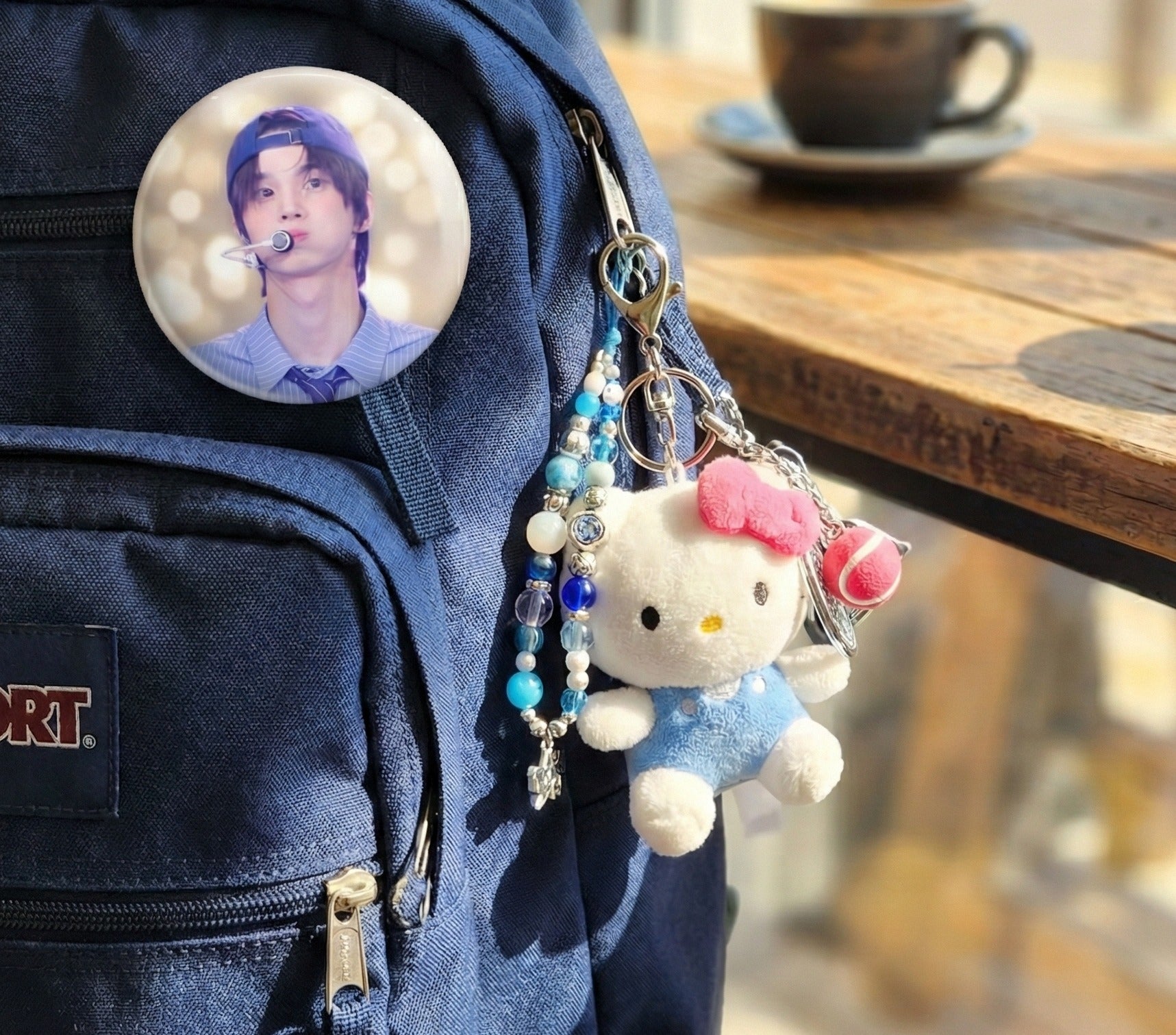 Hello Kitty tennis keychain layered with beaded keychain and K-pop photo card badge on backpack