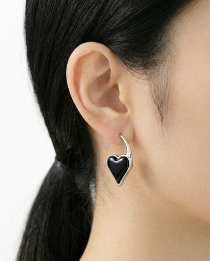 Black onyx heart hook earring in silver, worn on ear with clean side profile and pulled-back hairstyle.