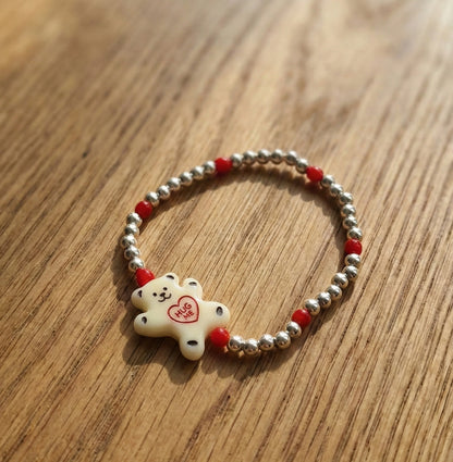 Milky white Hug Me bear silver ball bracelet with red seed bead accents on wooden background — Y2K kidcore aesthetic