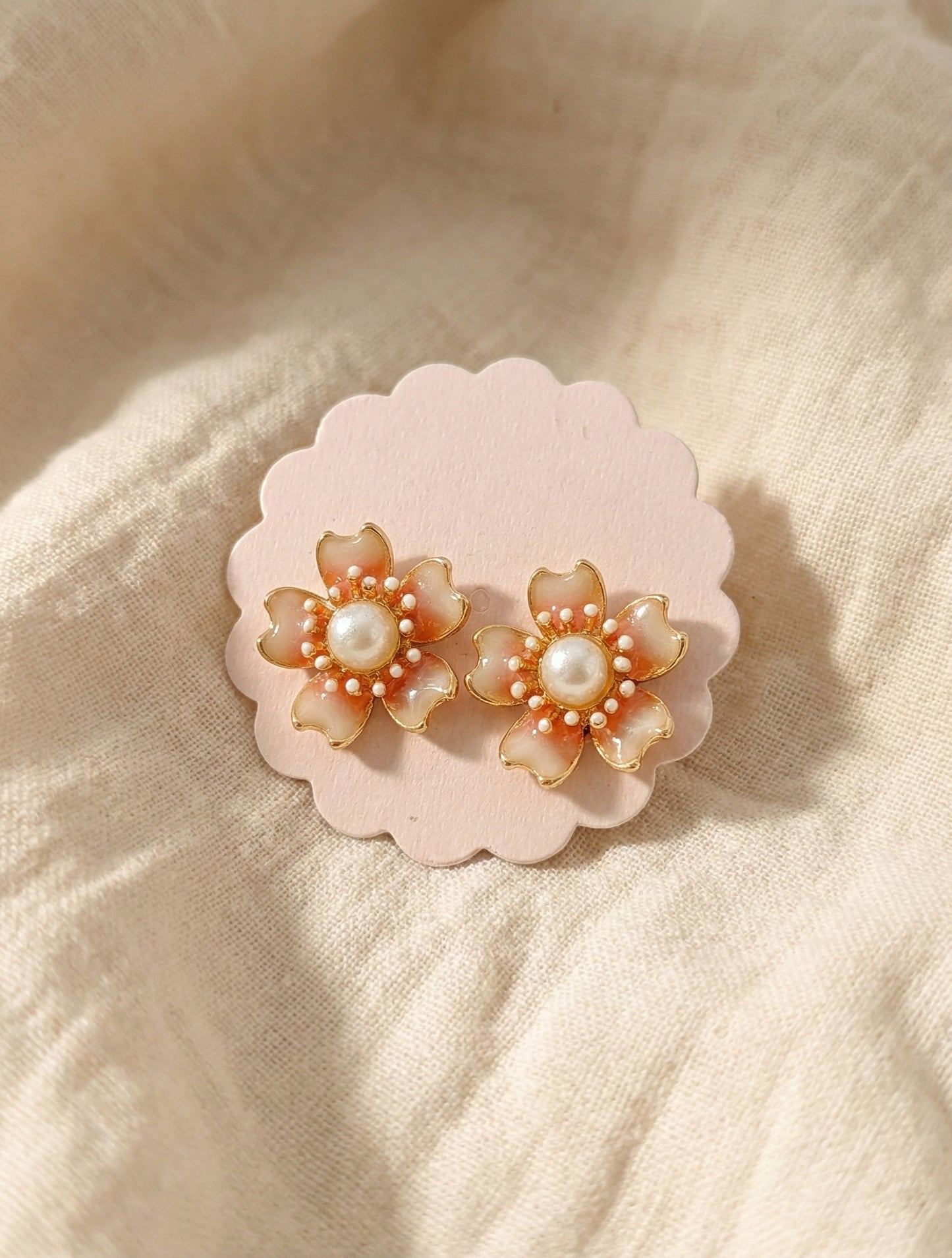  Peach coral flower earrings with gradient enamel finish and central pearl on pink scalloped display card