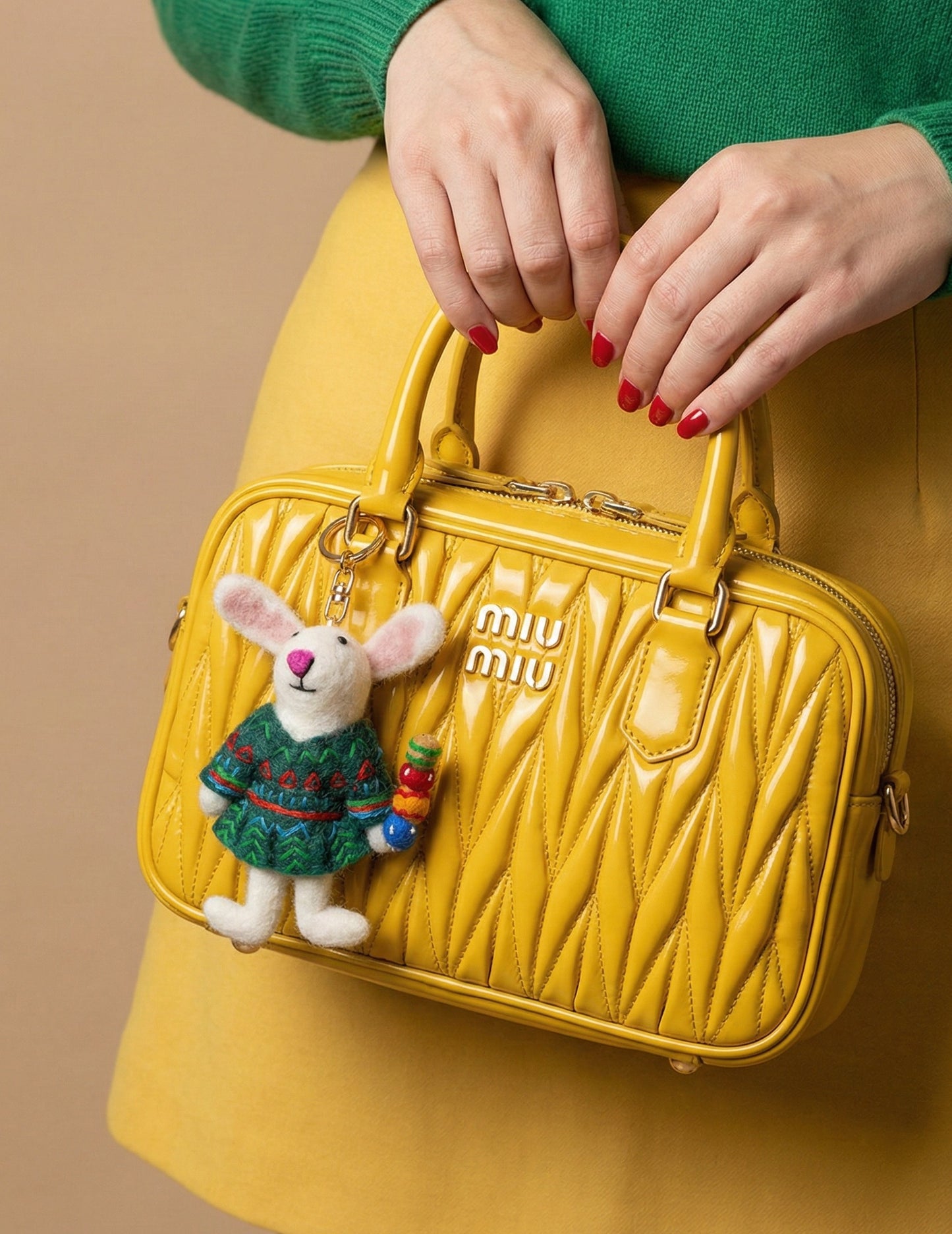 Yellow Miu Miu handbag styled with cute rabbit wool felt bag charm and red manicure