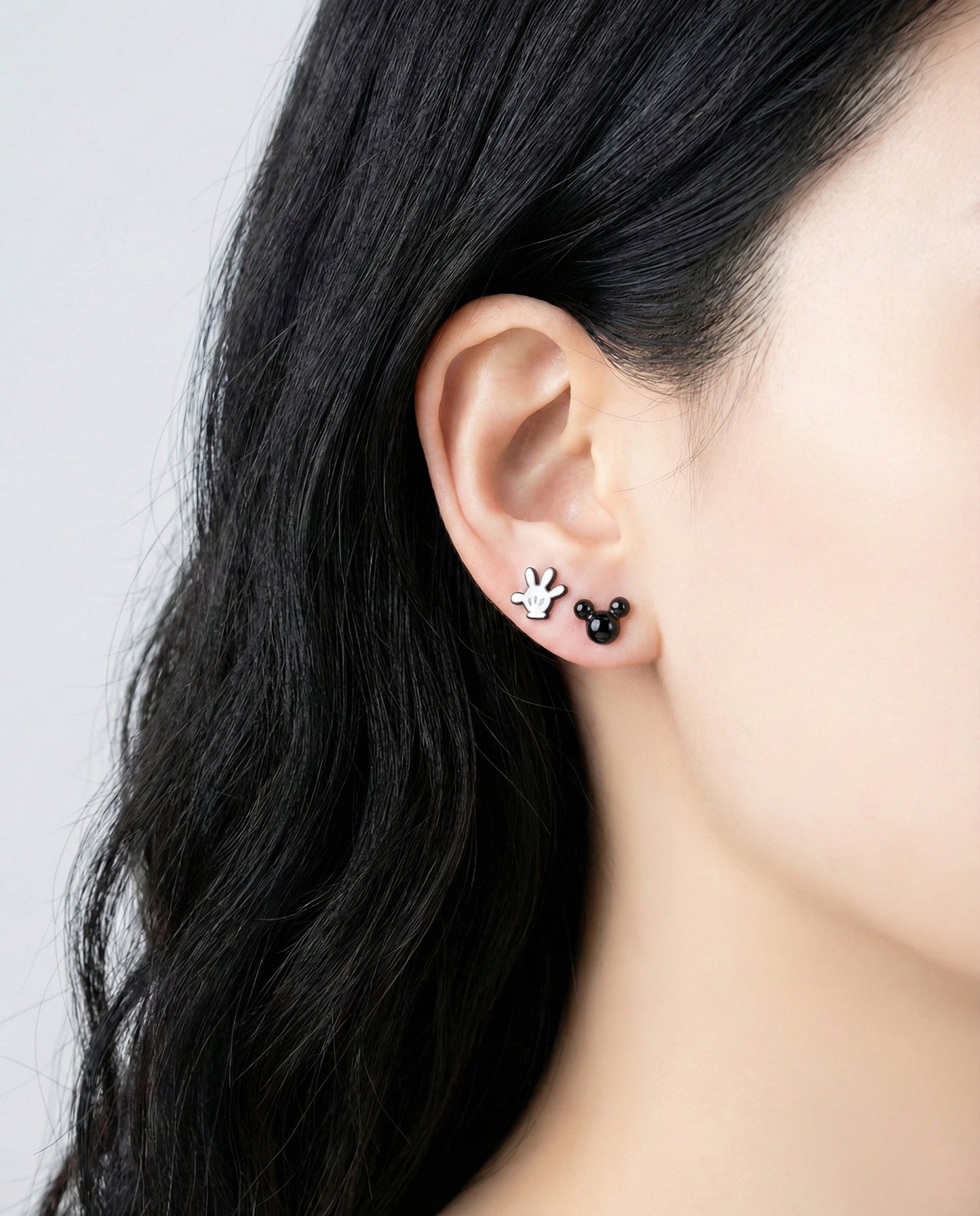 Model wearing Mickey white glove and black Mickey head stud earrings demonstrating layered ear styling