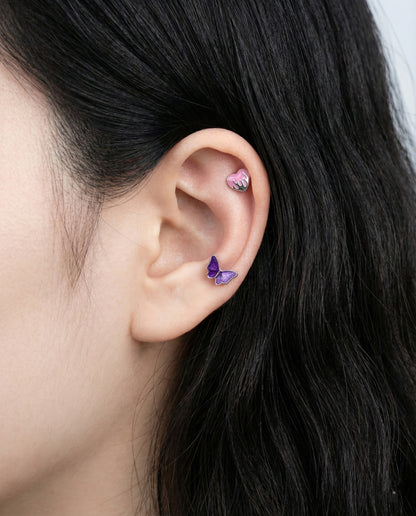 Purple melting heart piercing on helix with butterfly stud on lobe showcasing emo aesthetic ear styling