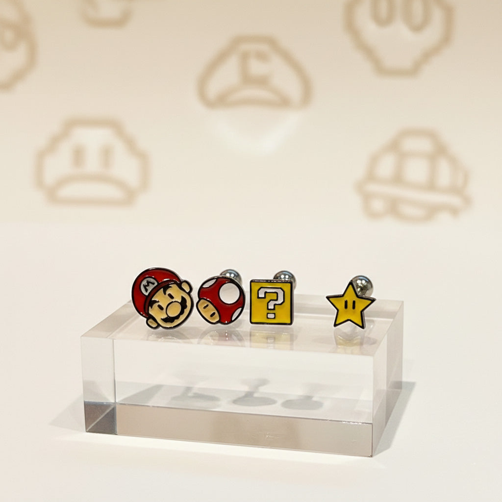Four Super Mario-themed barbell earrings displayed on a clear acrylic block: Mario face, red mushroom, yellow question block, and yellow star.