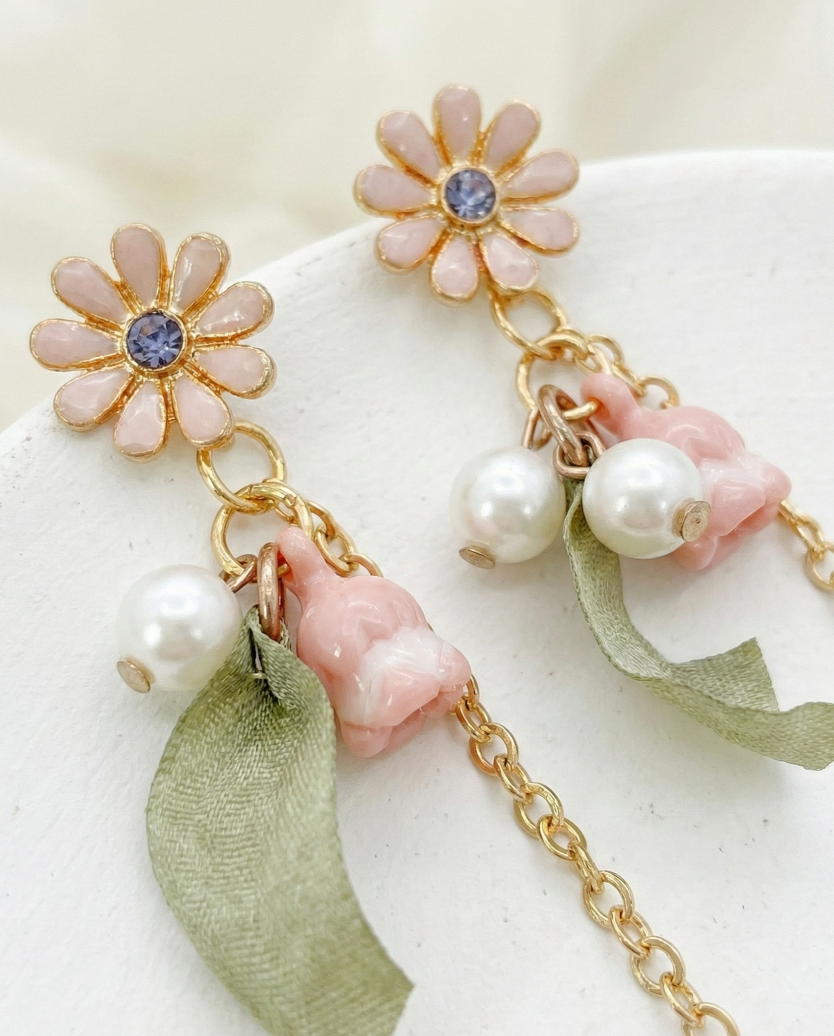 Detailed macro shot of the pink daisy stud, floral bells, and brass chain.