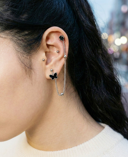 
Black butterfly and rose connected chain piercing worn on helix and lobe with white sweater