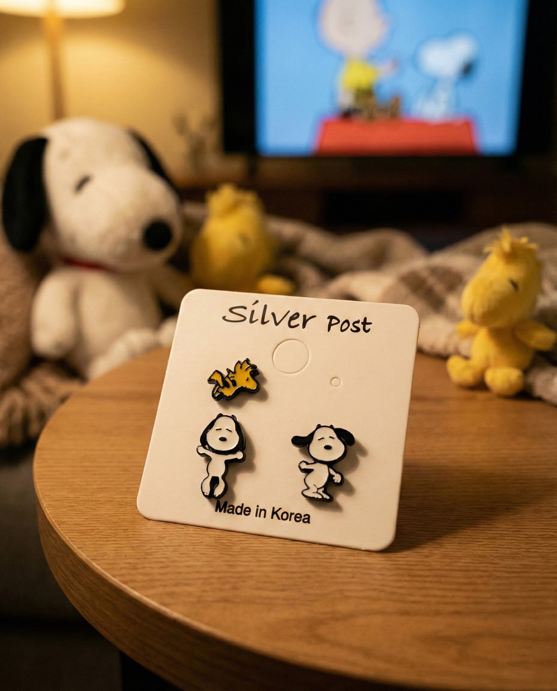 Cozy bedroom scene with Snoopy earring set card and plush toys