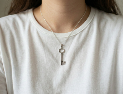 Front view of the silver key pendant hanging on a delicate 925 silver chain over a white crew neck.