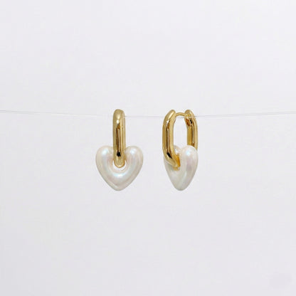 Pearl white heart charm earrings with glossy acrylic finish and gold huggie hoops