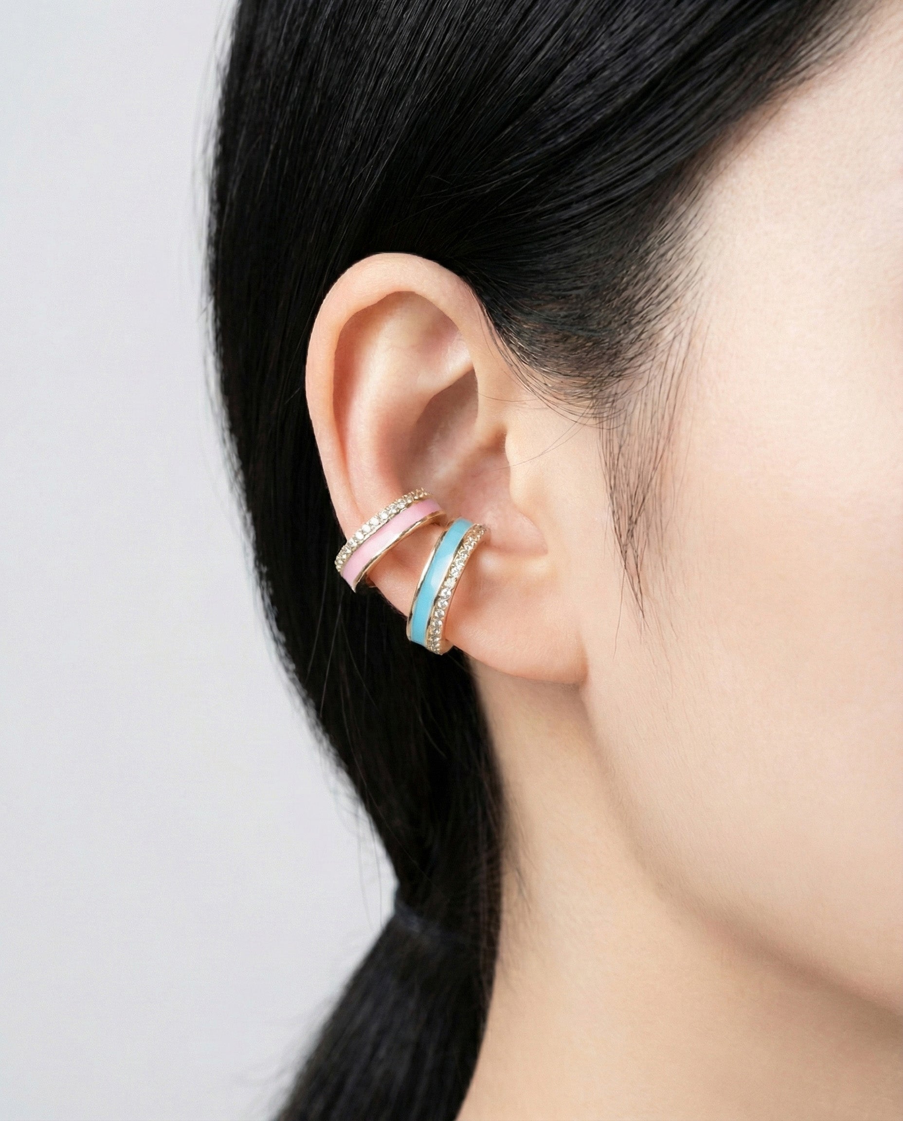 Turquoise and pink enamel ear cuffs with gold base and crystal detailing, stacked on helix