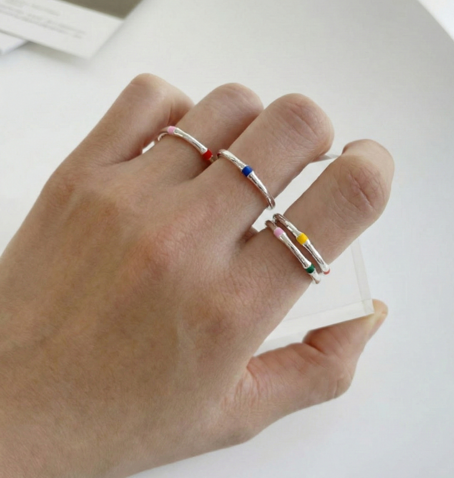 Hand shot showing three 925 silver enamel open rings worn on different fingers simultaneously, showcasing adjustable open band fit