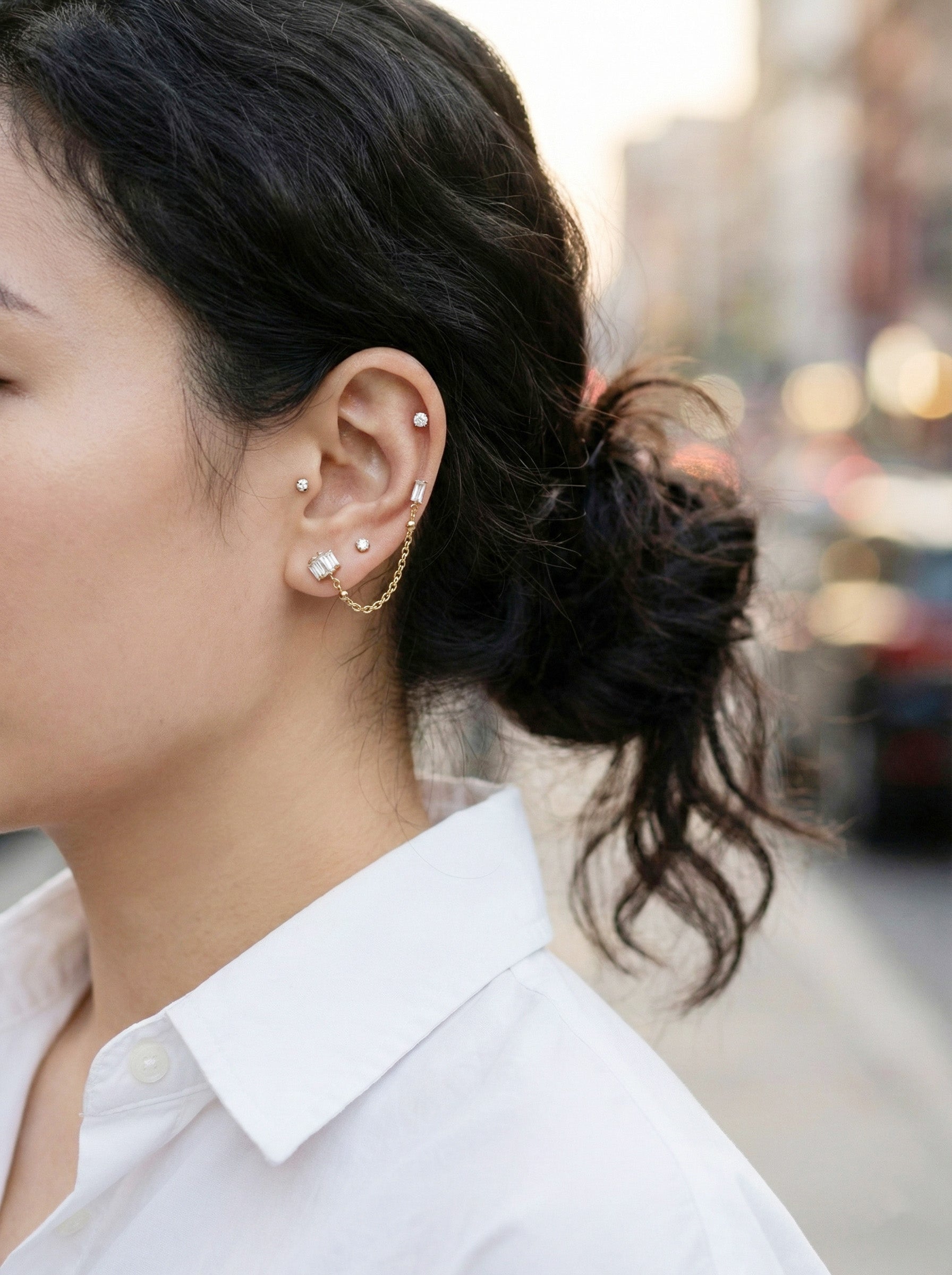 Side view of ear styling with double piercing chain studs and white shirt