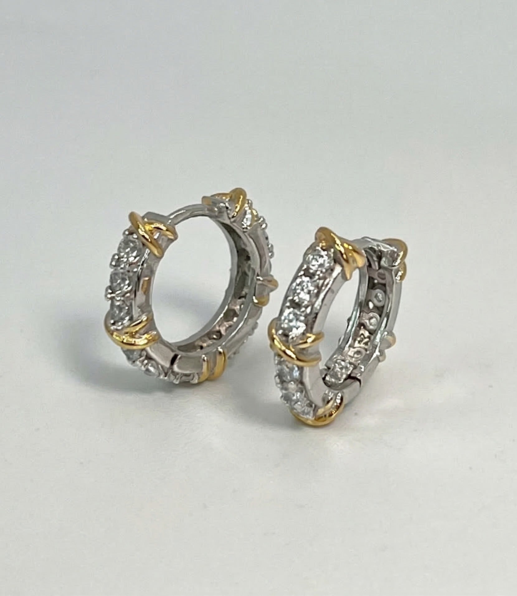  Pair of 925 sterling silver criss-cross huggie earrings with hinged clicker closure, white background 