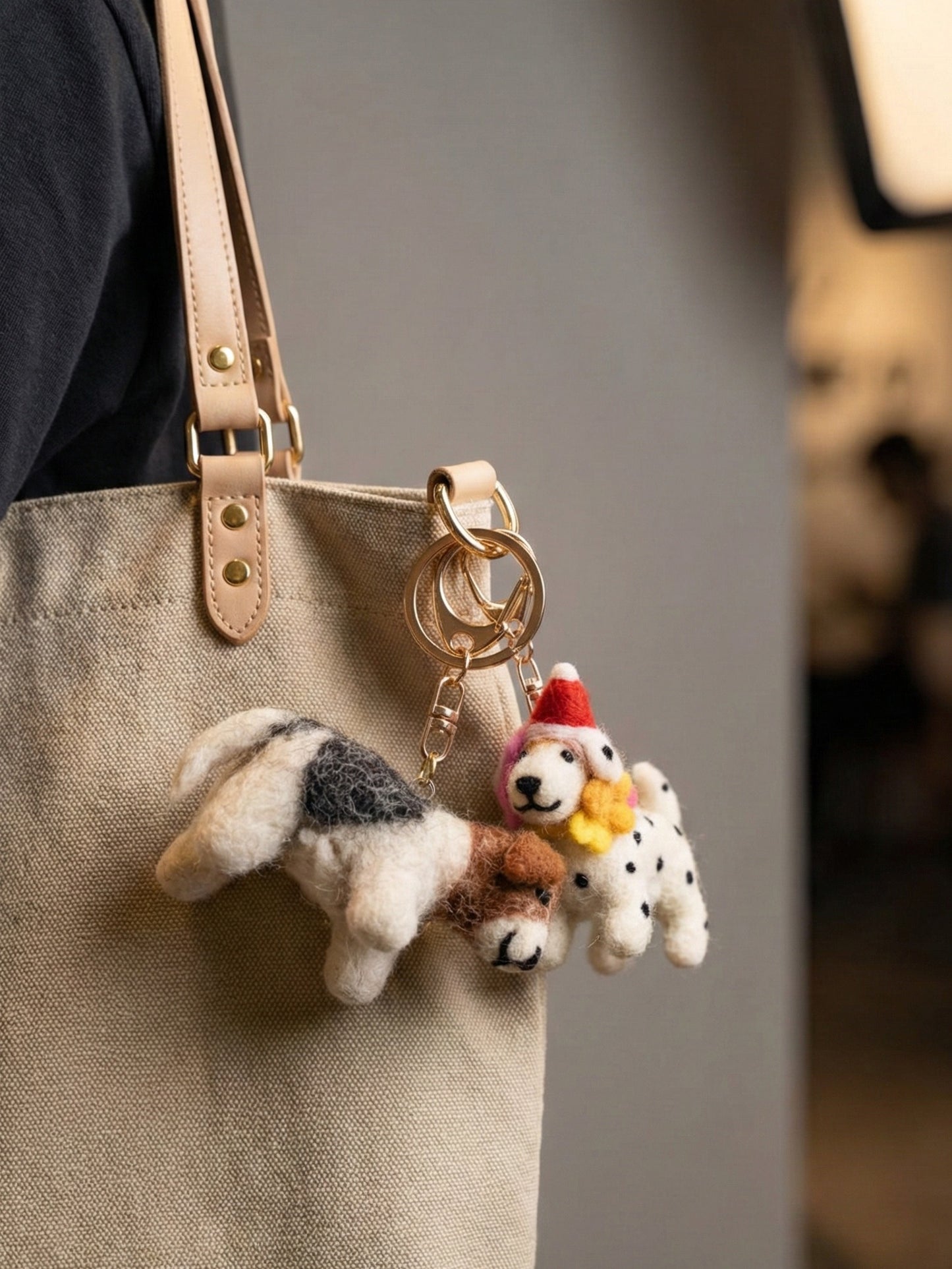Woman holding beige canvas tote bag with needle felted dog keychains hanging as bag charms