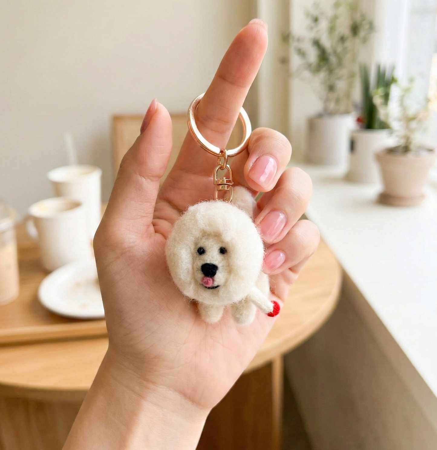 Hand holding small wool felt Bichon Frise keychain showing size
