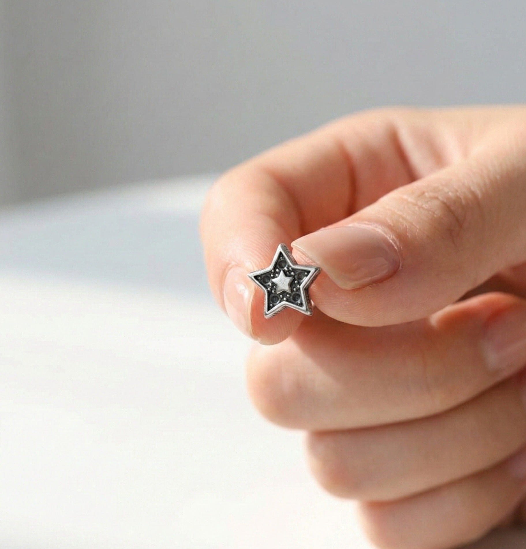 Hand holding an antique dot star barbell stud earring showing inner star and dot detail