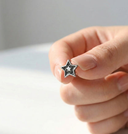 Hand holding an antique dot star barbell stud earring showing inner star and dot detail