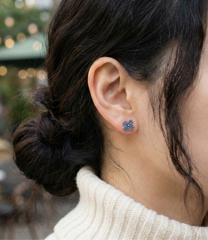 Woman wearing aqua blue clover stud earrings with ivory knit sweater outdoor natural light