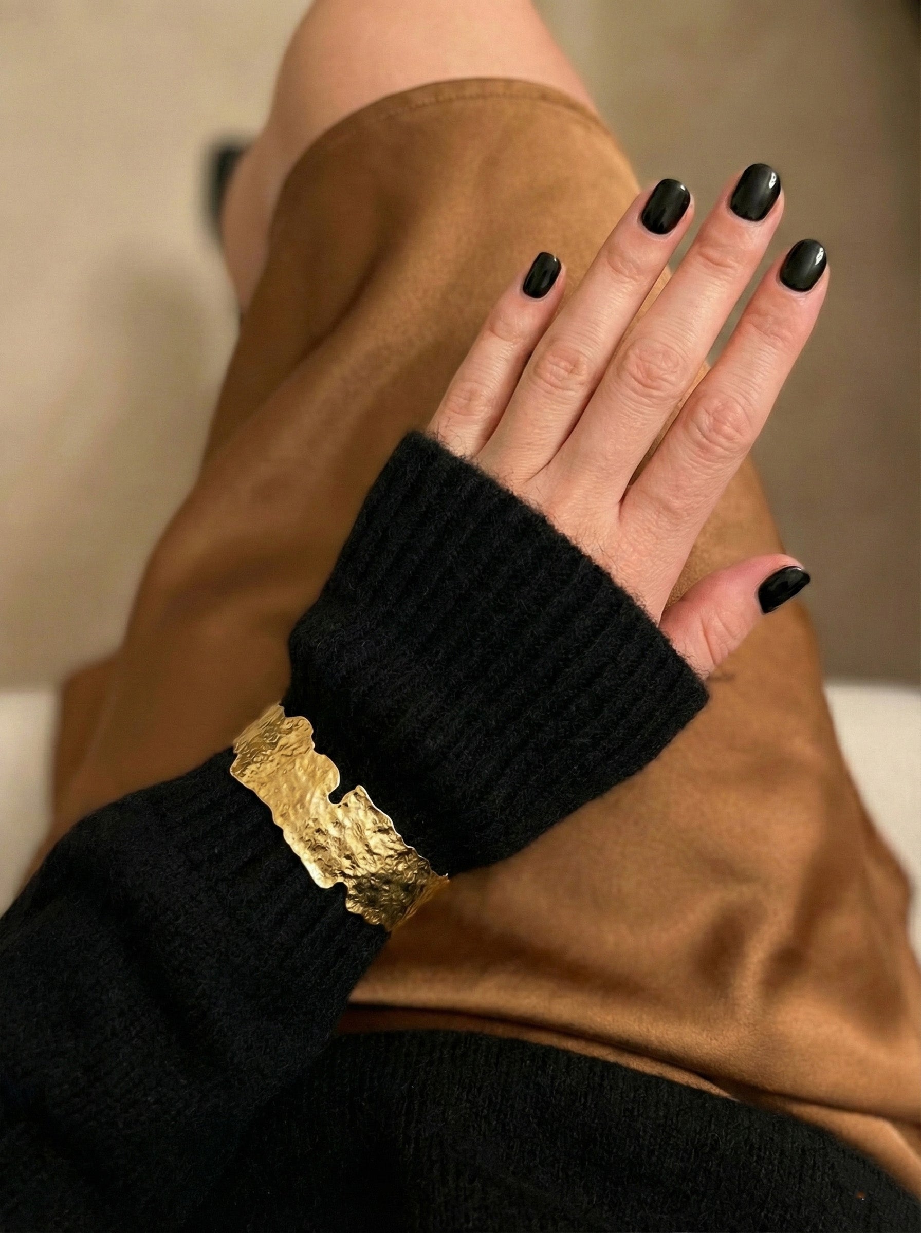 Gold hammered bangle over black sweater sleeve - vintage old money aesthetic jewelry