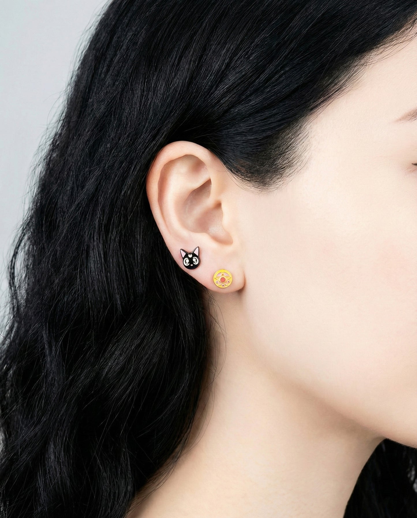 Model wearing Luna black cat and Crystal Star Compact pink brooch earrings on ear closeup