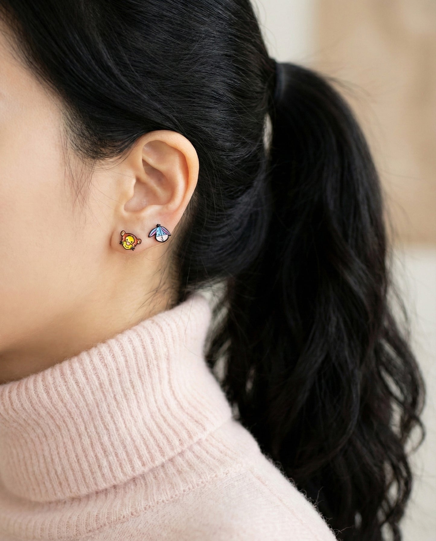 Tigger and Eeyore character earrings worn as double studs on ear lobe