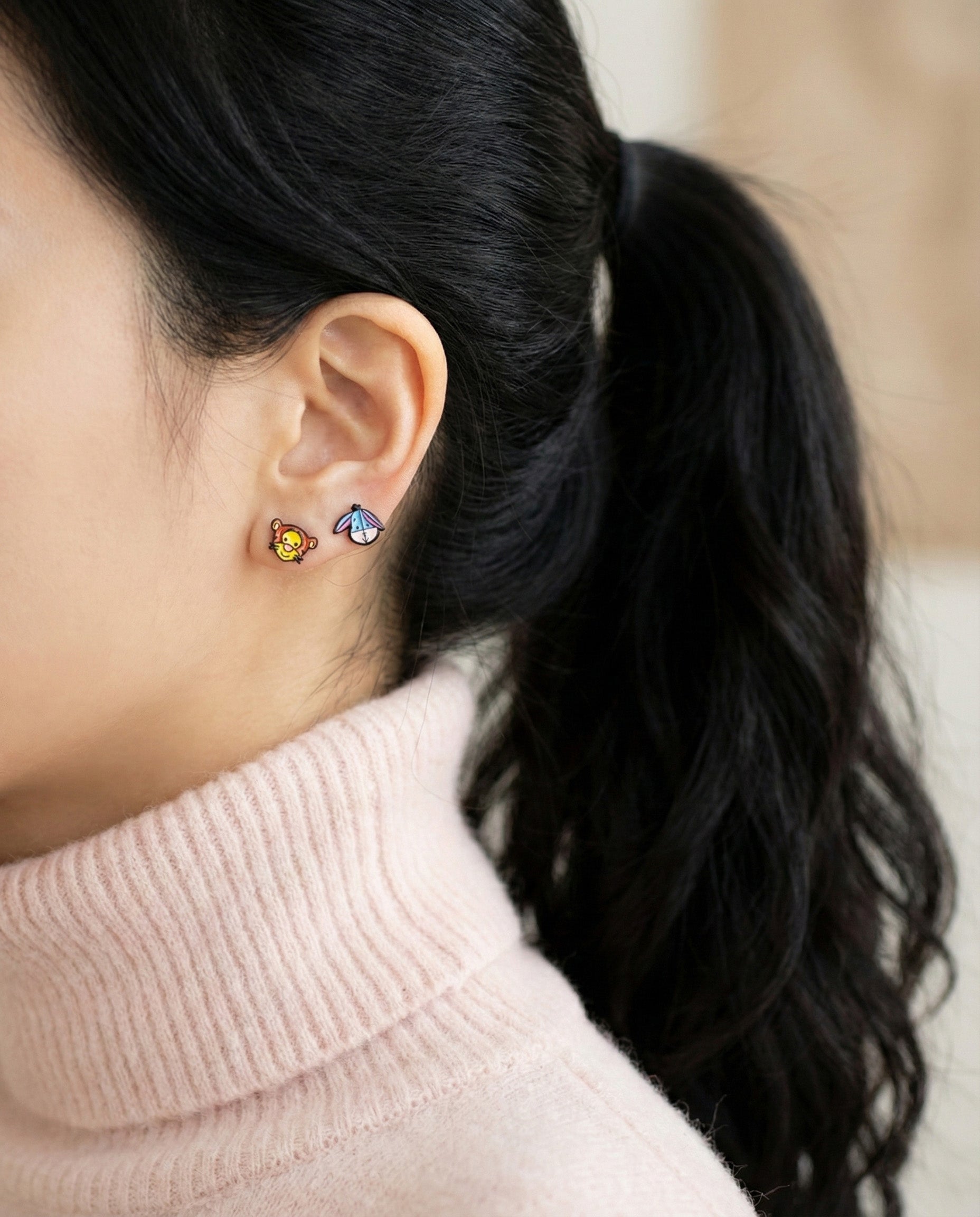 Tigger and Eeyore character earrings worn as double studs on ear lobe