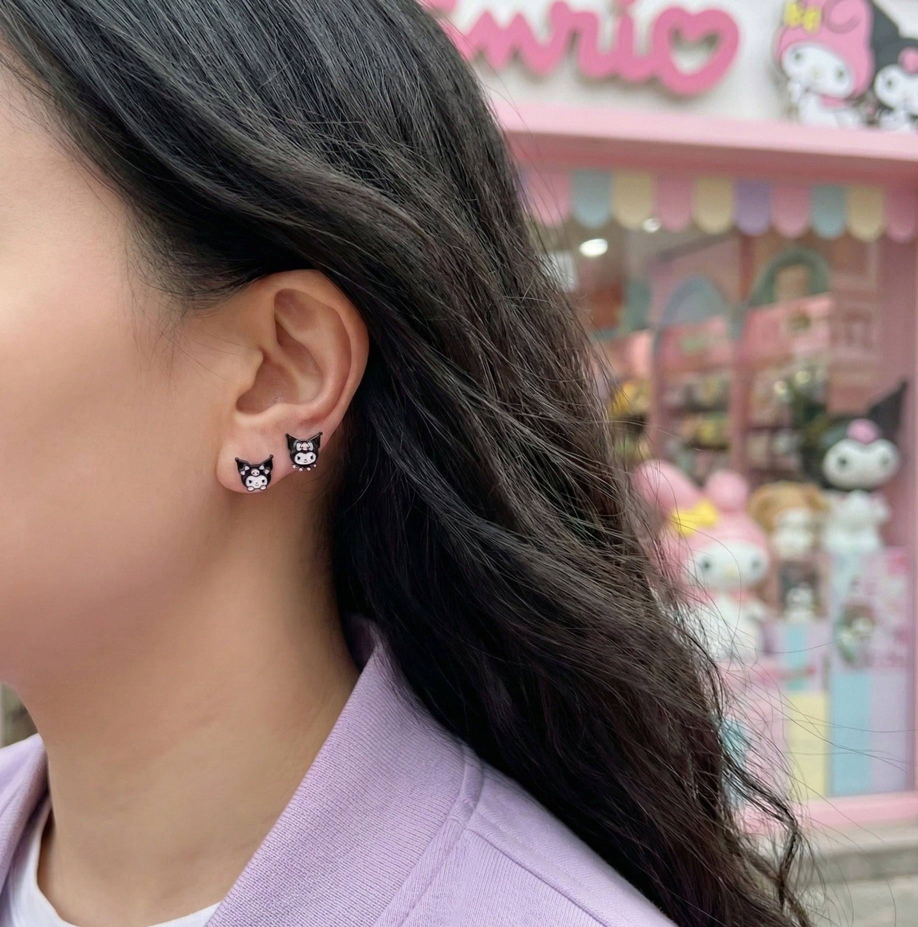 Model wearing Kuromi mismatched earrings with lavender purple sweater showing side profile