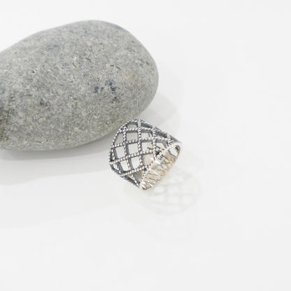 Single 925 sterling silver lace lattice bold wide band ring lying on white surface next to gray stone, showing beaded diamond grid pattern and 925 stamp