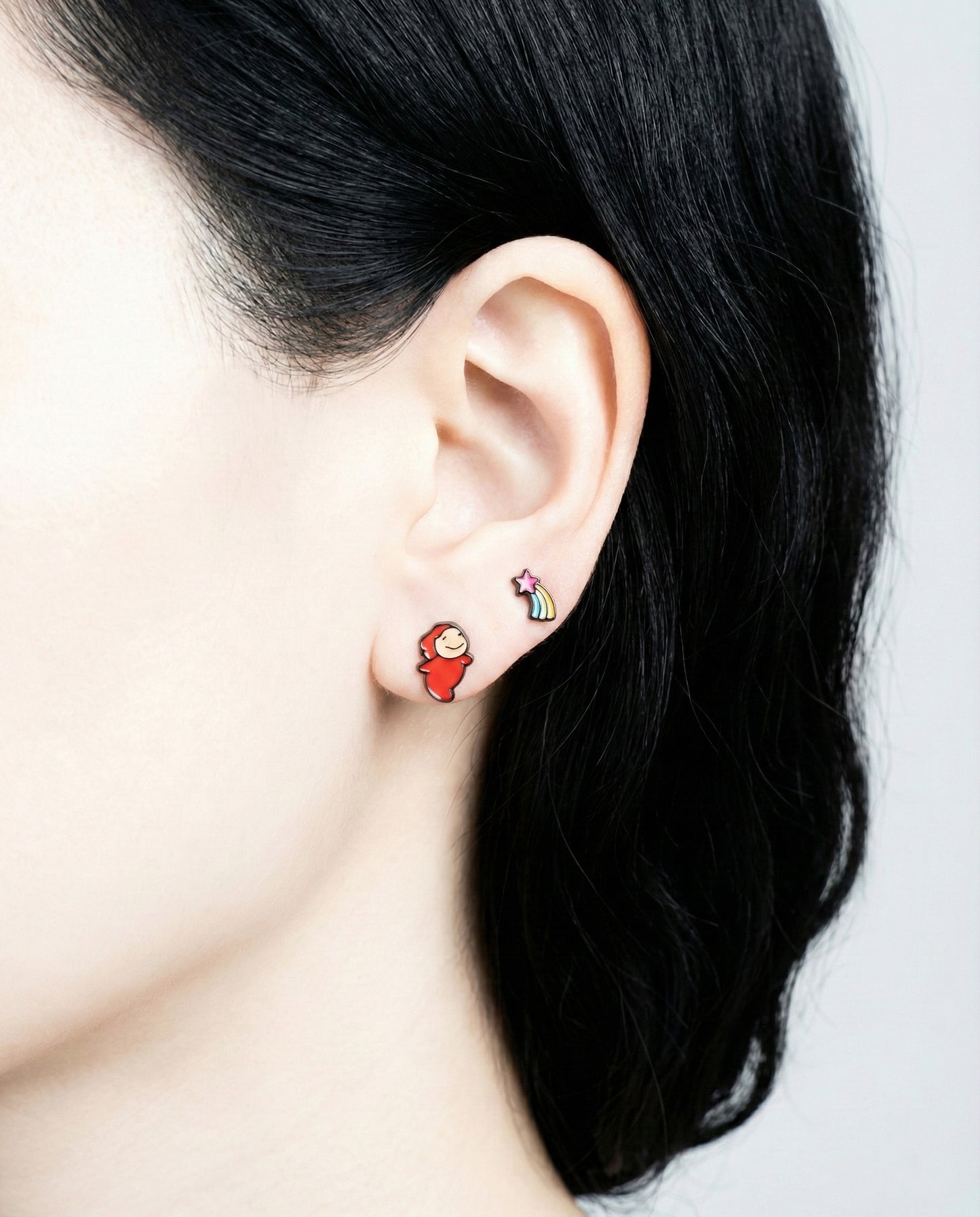 Model wearing Ponyo and rainbow shooting star stud earrings, front view