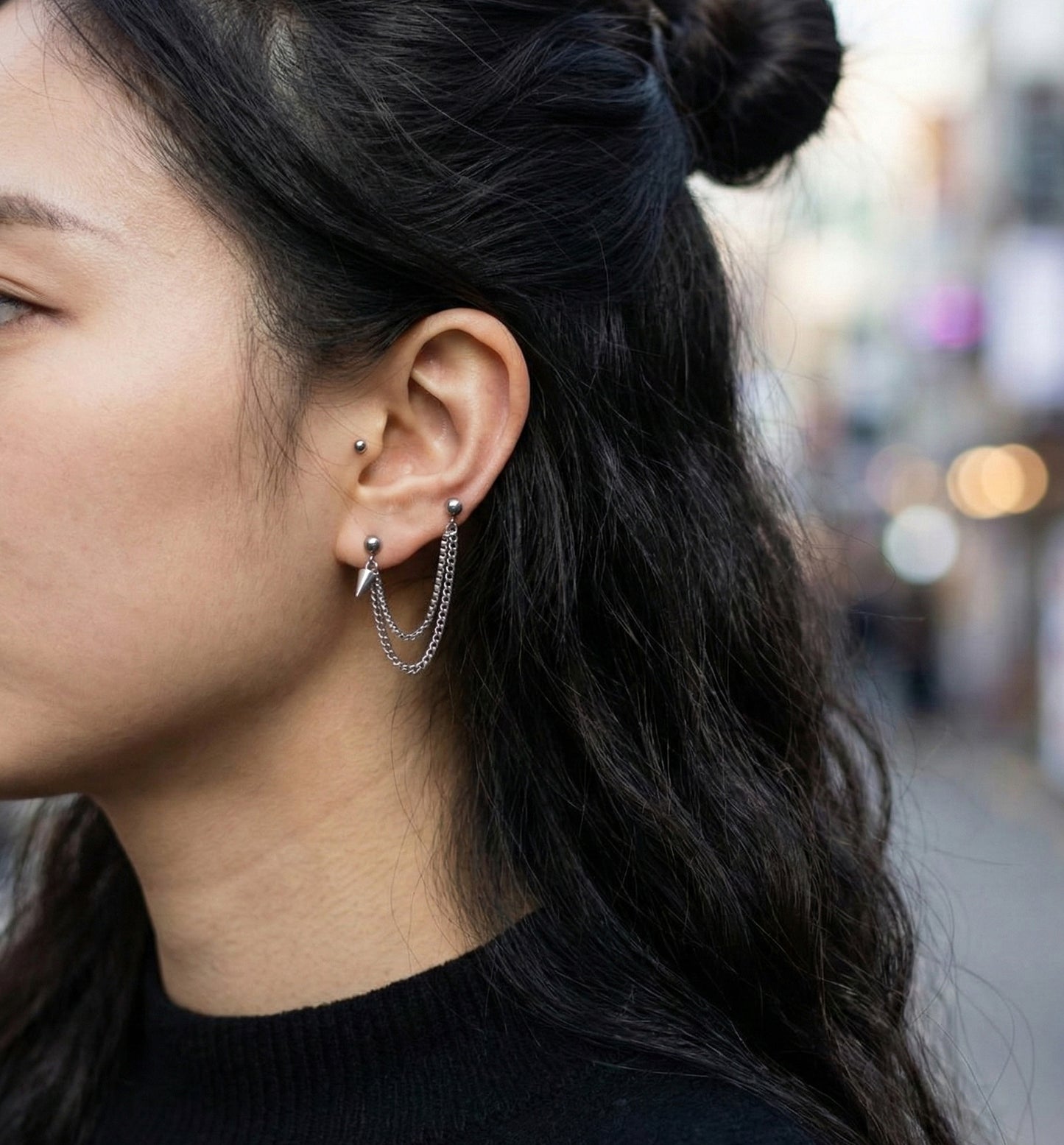 Close-up of layered chain piercing with spike pendant on ear  
