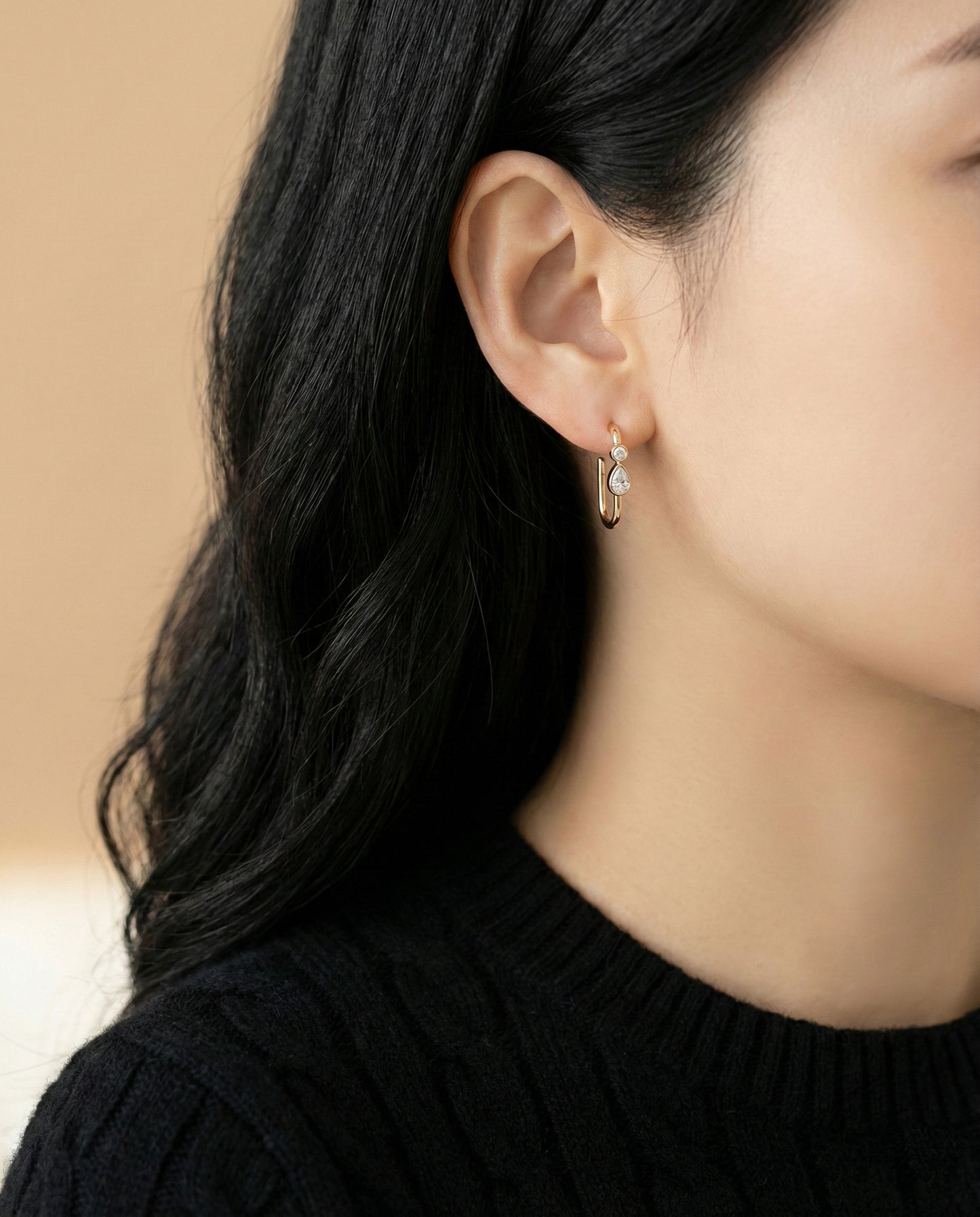 Front view of gold bezel-set teardrop CZ layered hoop earrings worn by model*